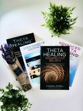 Fotografia de quatro livros escritos por Vianna Stibal, próximo a estes há dois vasos com folhagem e um arranjo de flores de lavanda embrulhadas em papel pardo